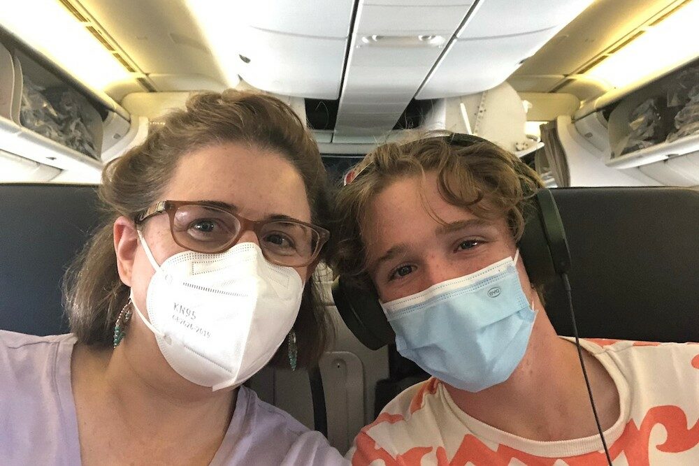 woman and son wearing masks on a plane