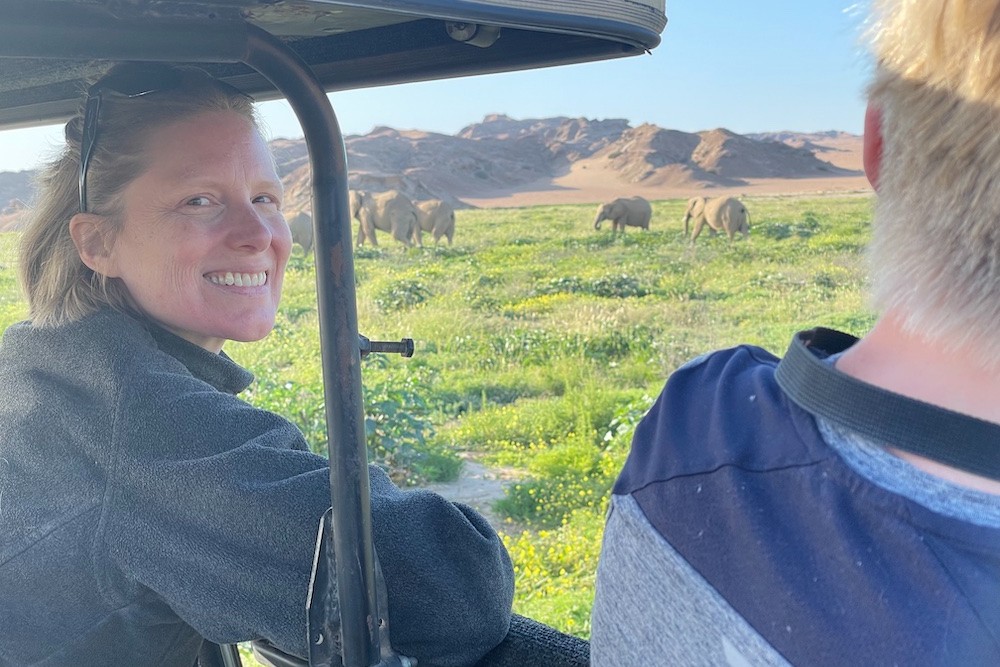 mother and son tourists in jeep looking at elephants in grassland in Namibia on safari