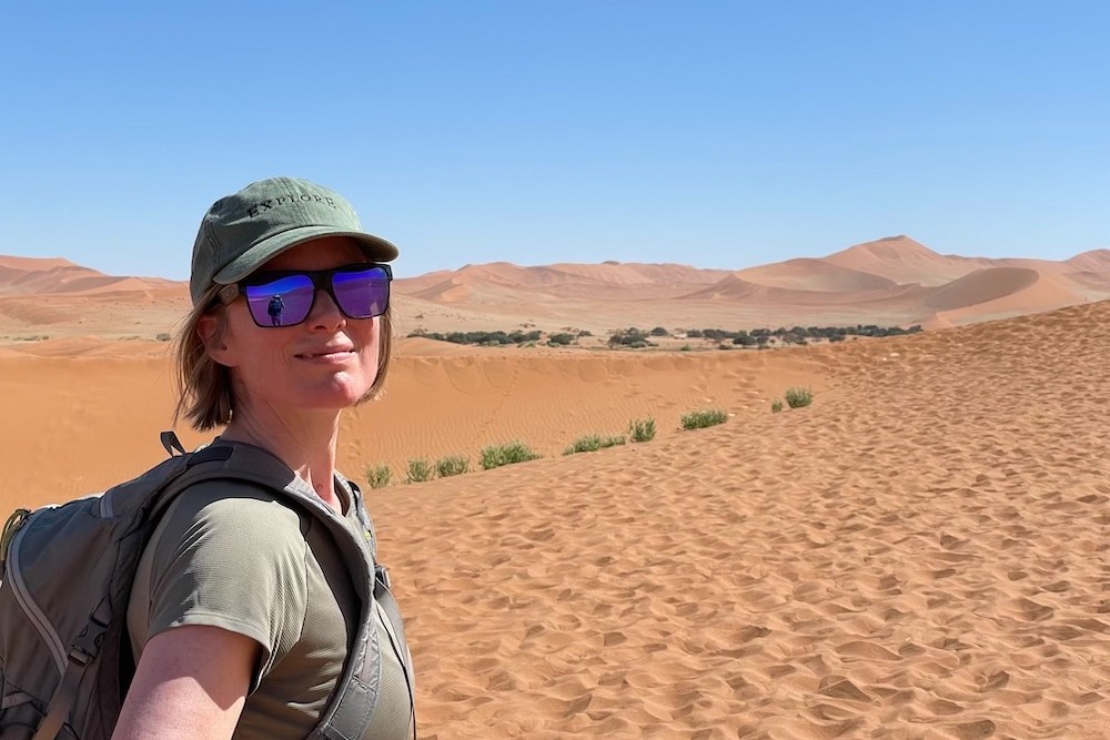 woman posing in Namibia desert with hat and sunglasses