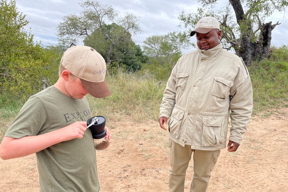 Our tracker in Sabi Sabi, Lesley, teaches my son how to grind coffee in the bush.  South African safari