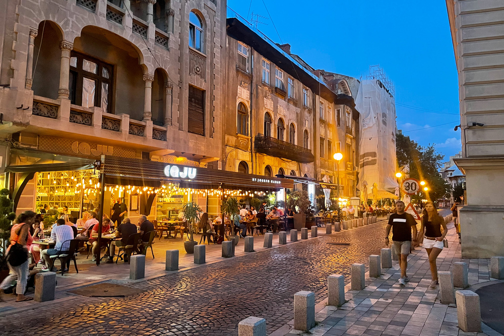 A cafe and people walking in the boulevard in Bucharest, Romania.
