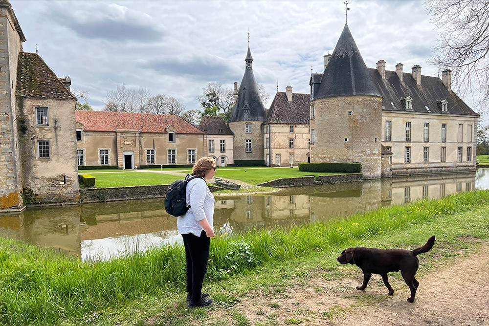 Wendy at Chateau de Commarin in Burgundy, with a dog approaching her.