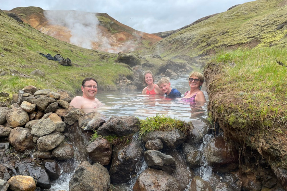 Brook Wilkinson and her family enjoying hot springs with beautiful mountains in the background.