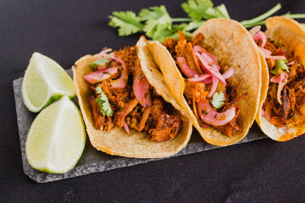 Mexican tacos filled with cochinita pibil ( shredded meat, onion and spicy), coriander and lime.
