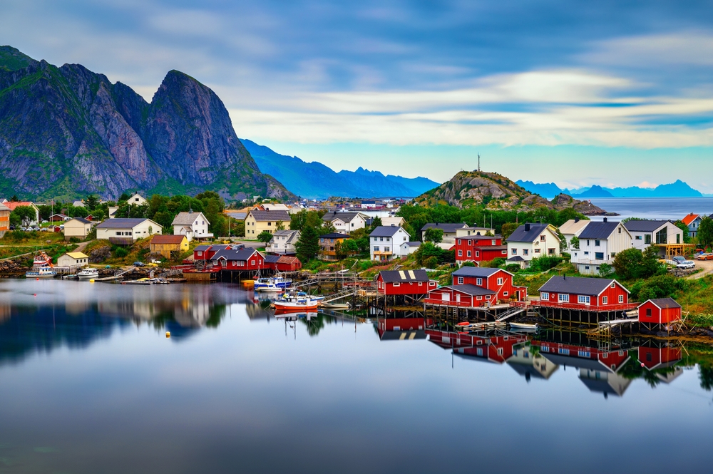 Reine village with traditional red rorbu cottages, fishing boats and high mountains in the background on Lofoten islands in Norway.