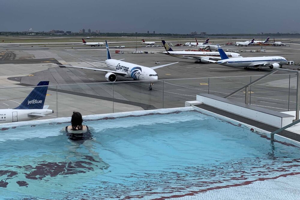 Carolyn in the TWA Hotel's pool looking at the parked airplanes.