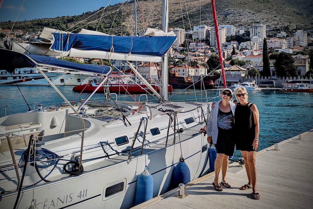 Travelers next to a private sailboat on the coast of Dubrovnik, Croatia