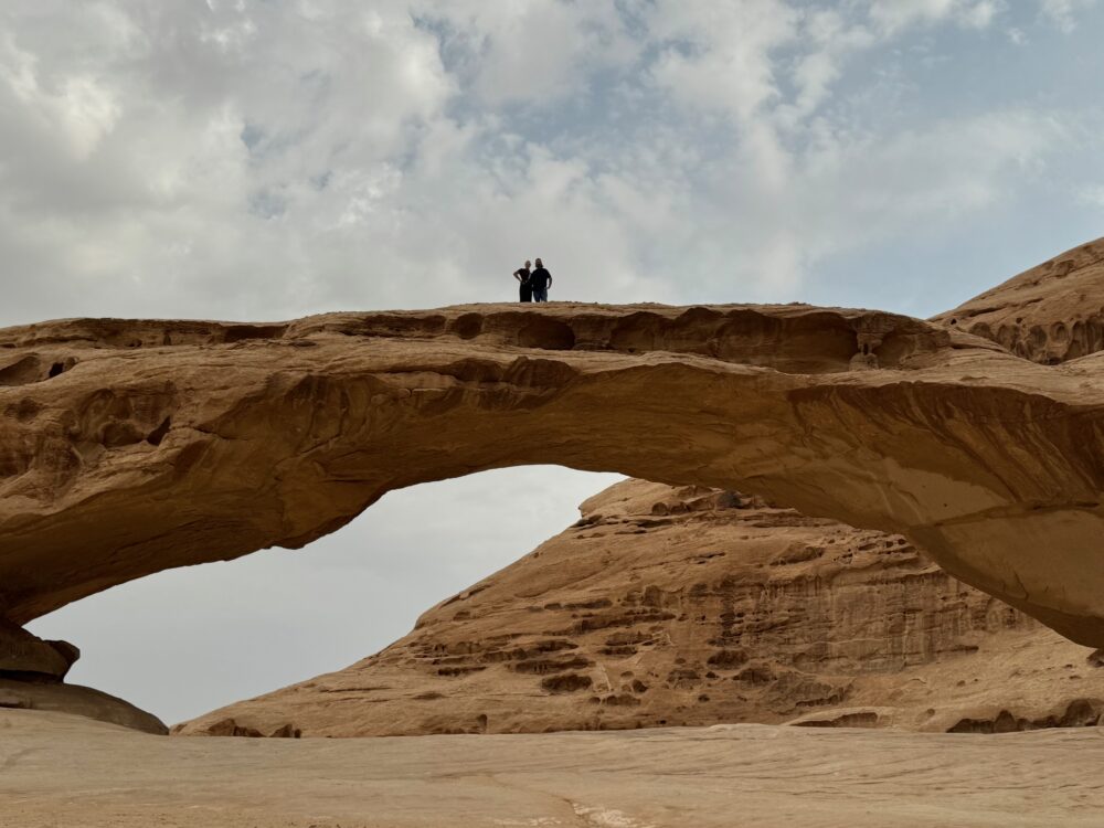 Our travelers, Amy Evers and her husband atop a rock arch in Wadi Rum, Jordan.