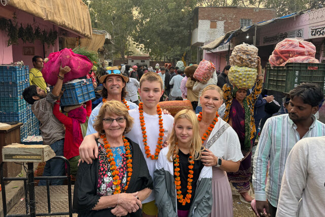 Amy Evers and her family at a produce market in Jaipur, India wearing marigold flowers.