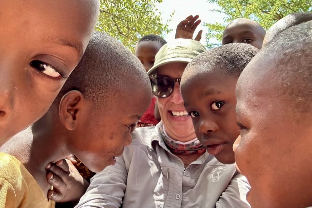 Traveler taking a selfie with with local kids during a community visit to the Mukundusi Village in Tanzania.