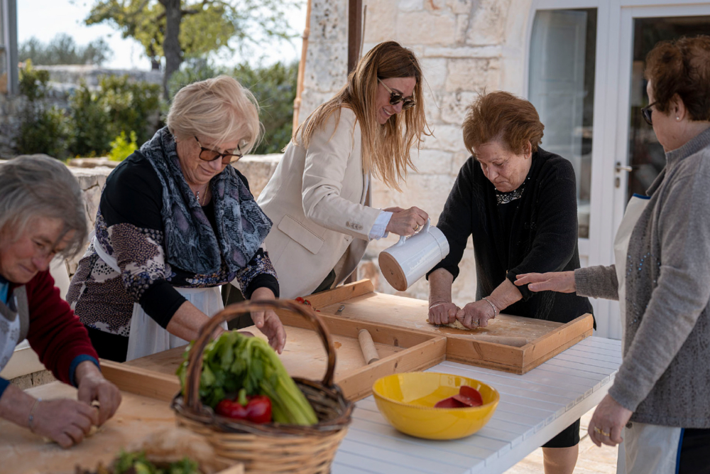 Italian grandmothers preparing fresh pasta dough outdoors.