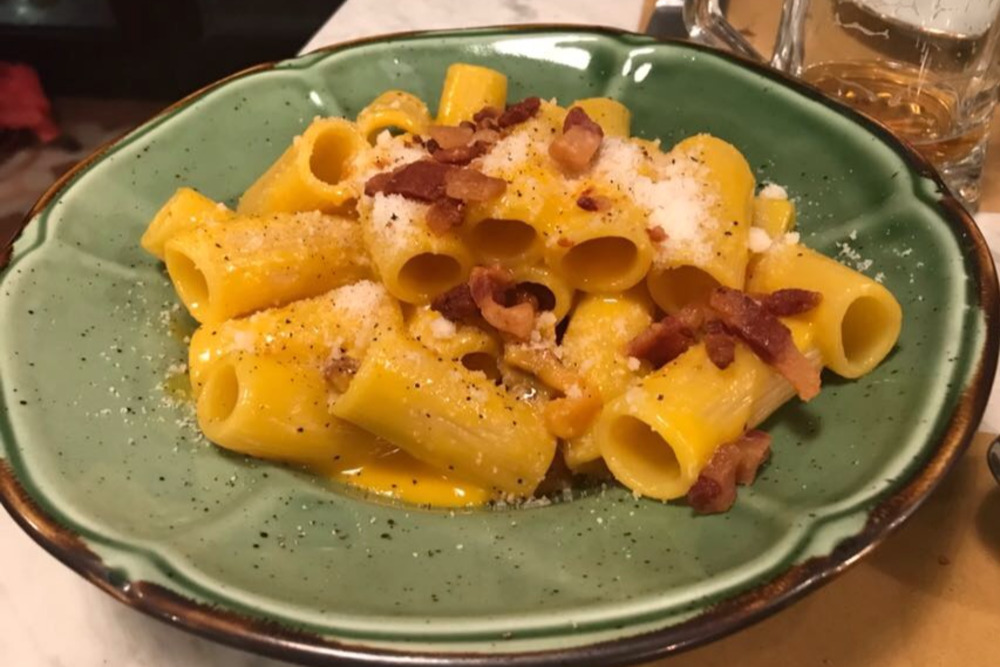 Pasta carbonara on a plate with parmesan and guanciale.