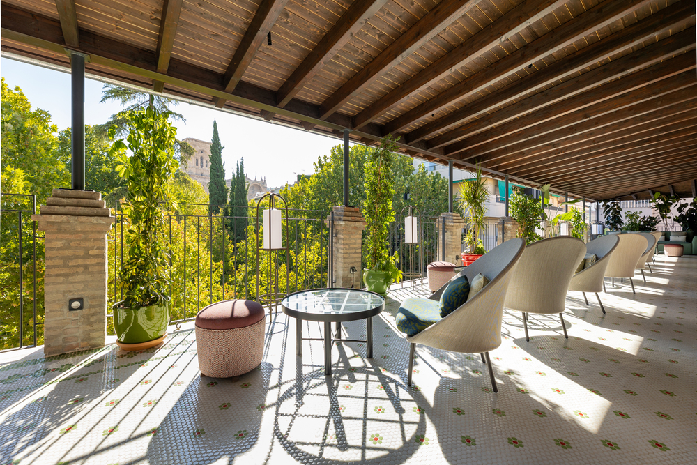 The Seda Club's rooftop terrace on a sunny day overlooks a leafy plaza in Granada, Spain.
