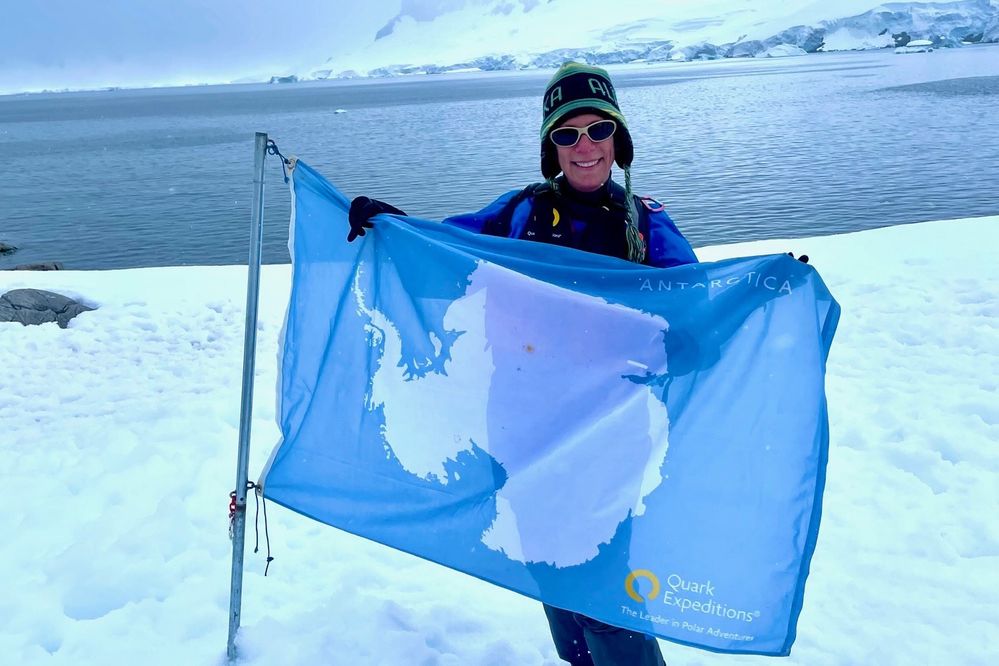 Traveler Milinda Martin holding up an Antarctica flag after setting foot on the continent near Cierva Cove.