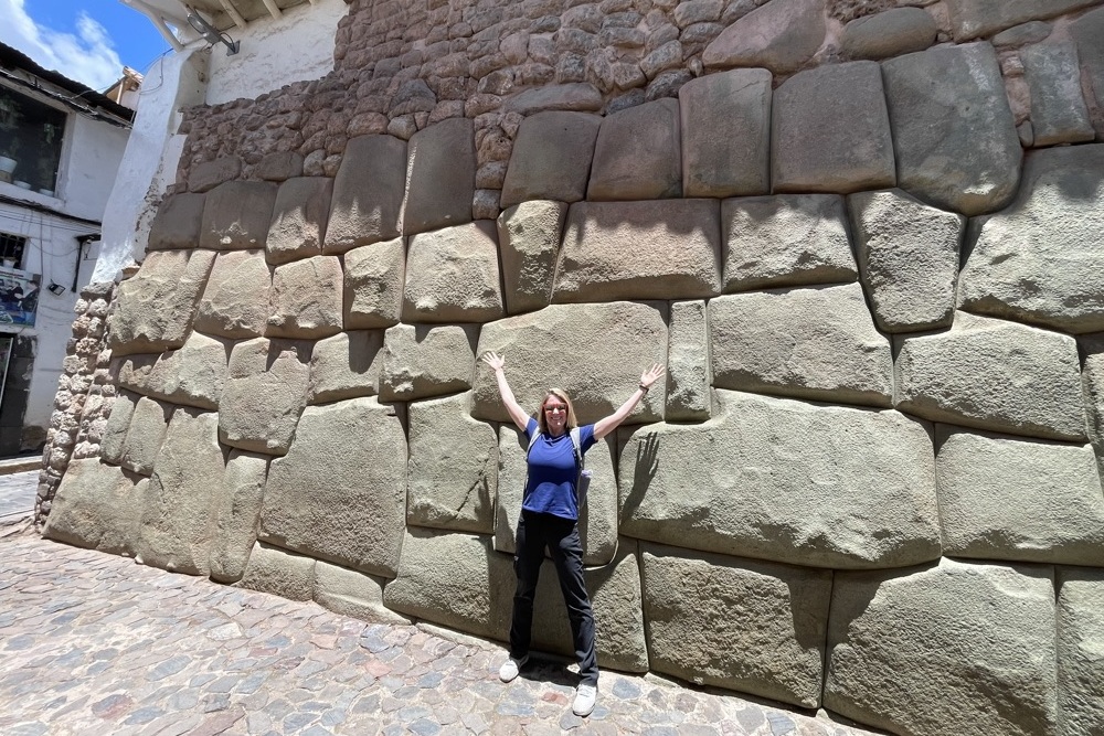 Brook with raised hands in front of the Inca wall.
