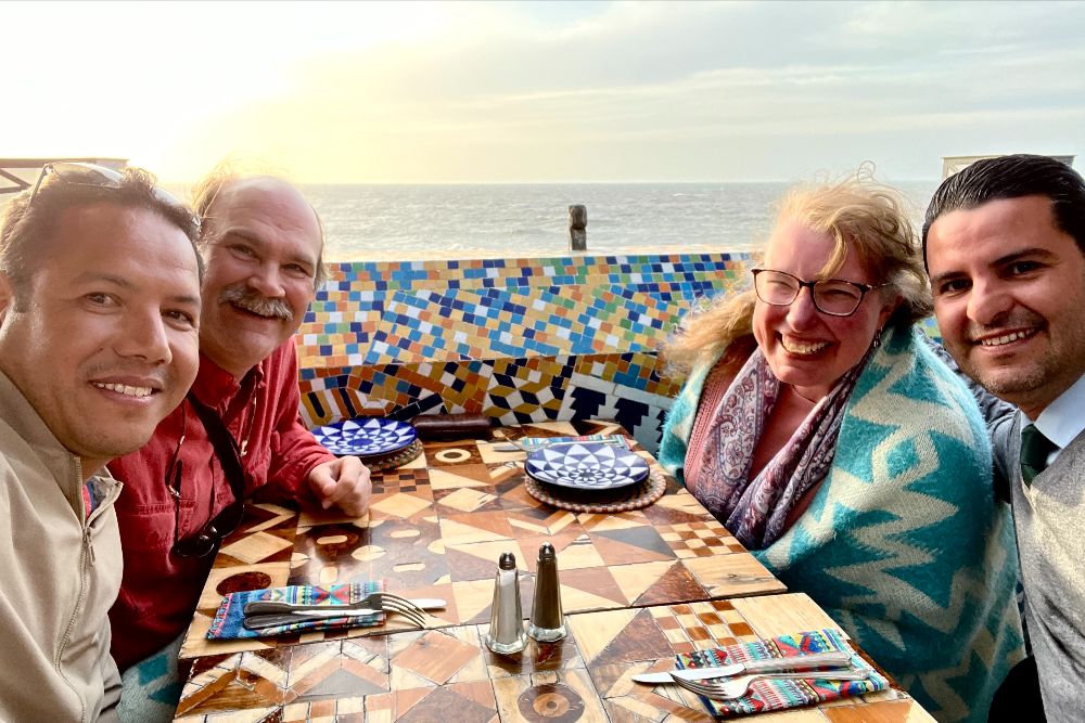 Travelers Craig and Stephanie Smith with their driver and guide having dinner on the rooftop terrace of Essaouira's Salut Maroc, Morocco.