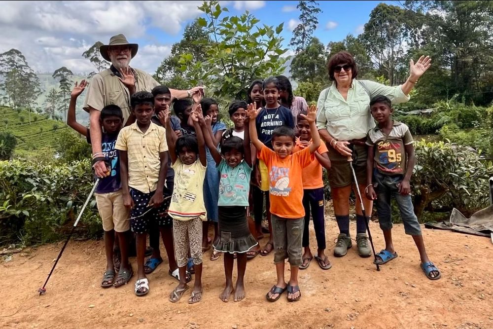 Travelers surrounded by village kids on their Tea Trail hike in Sri Lanka.