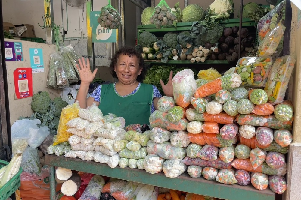 A vendor dressing in colorful clothes at the Lima market in Peru selling variety of vegetables.