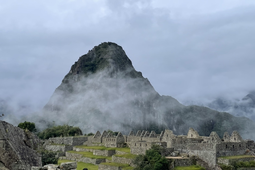 Machu Picchu on a cloudy day with mountains in the background.