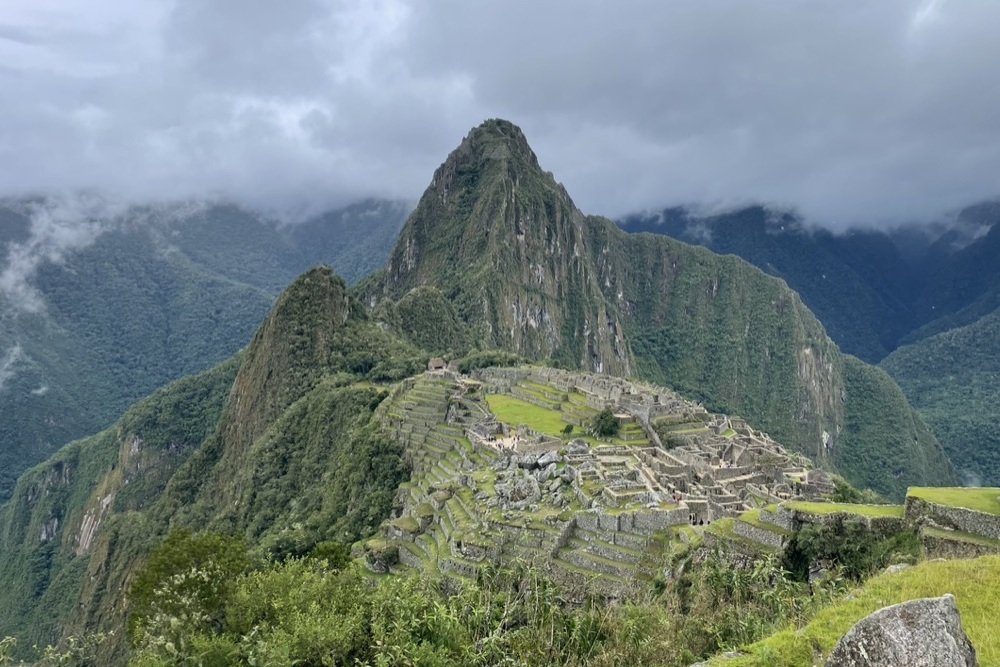 Machu Picchu on a cloudy day with mountains in the background.