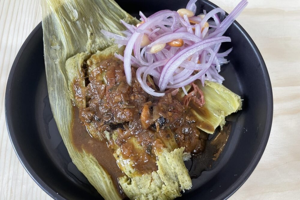 Over the top image of Tamale Cumpa on a black plate.
