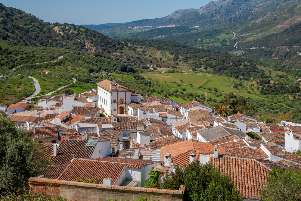 A village with white houses and a church surrounded by mountains.