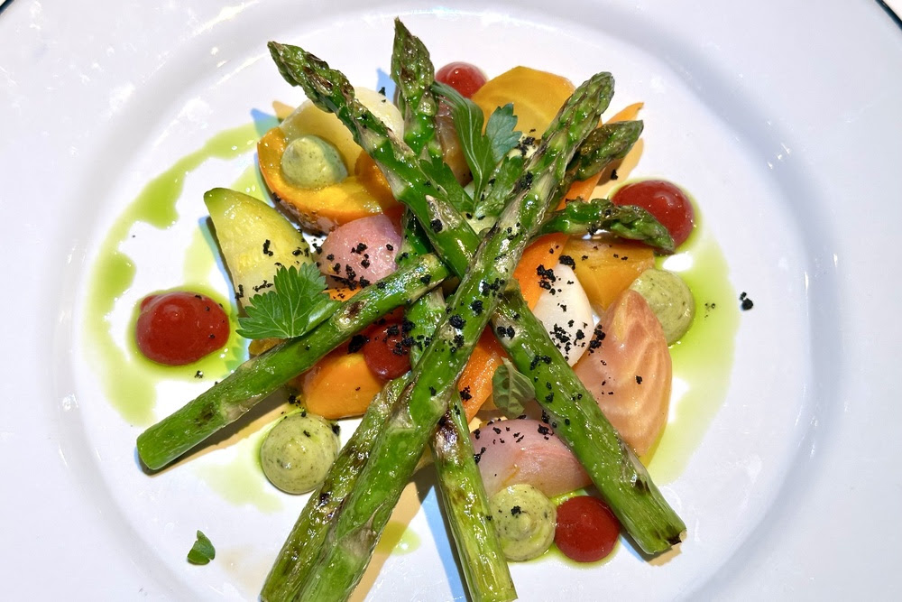 A plated, colourful dish with asparagus and other vegetables.