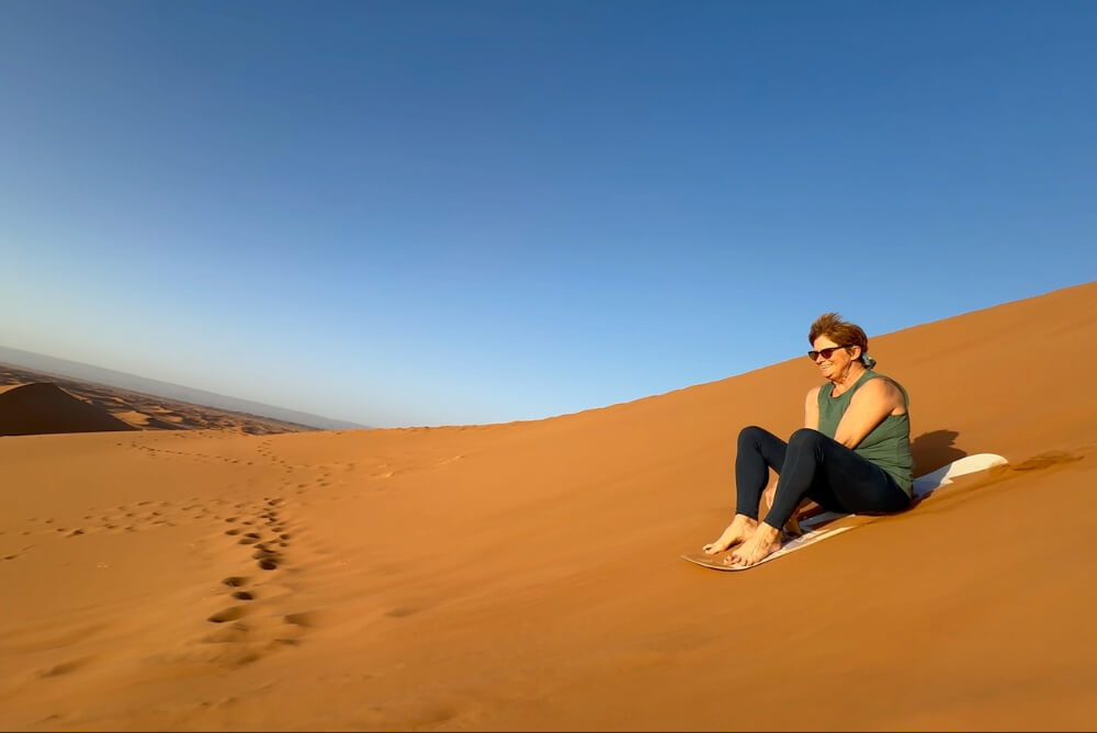 Susan Crandell sandboarding in the Sahara dessert in Morocco.