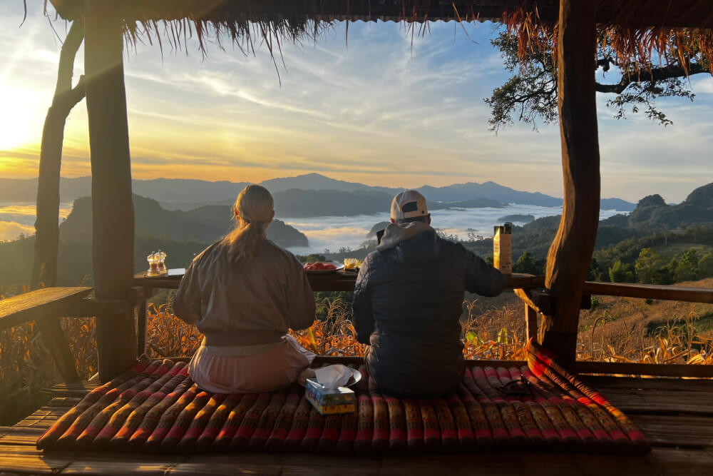 Amy and Chad having breakfast and watching the sun rise across the valley in Thailand.