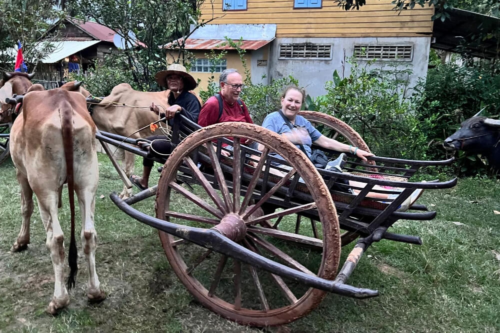 Julie and Max Silbermann riding in an oxcart in the Cambodian countryside.