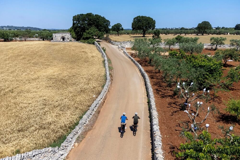 Two people biking on a road in Puglia, Italy.