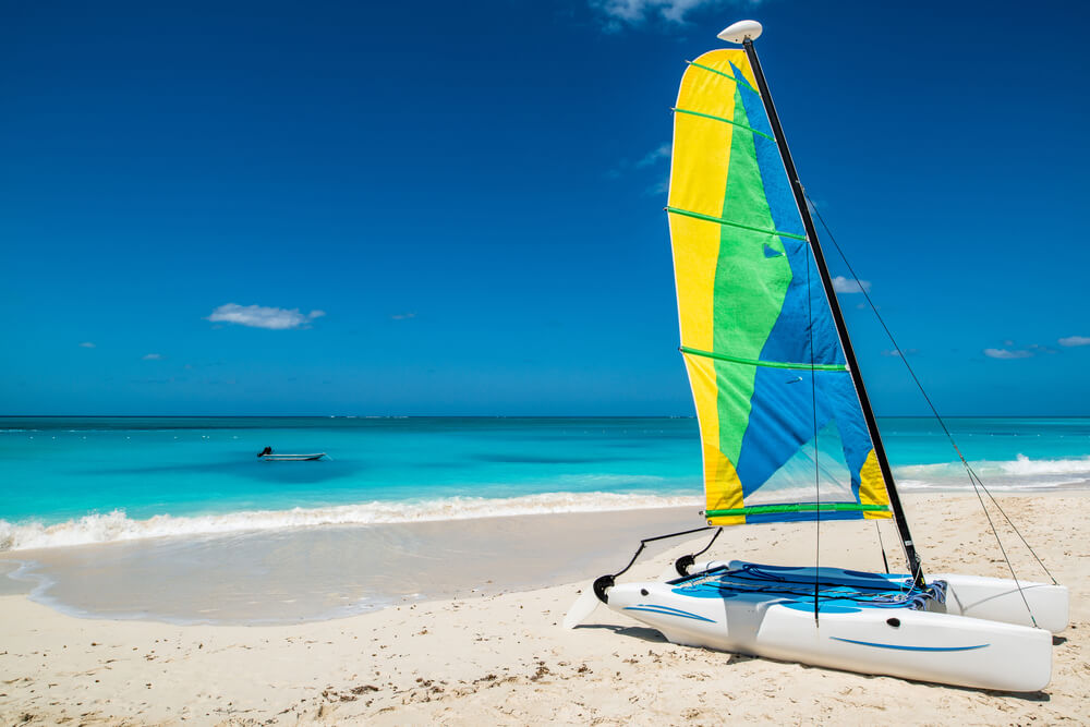 A sailboat on a sandy beach next to the ocean.