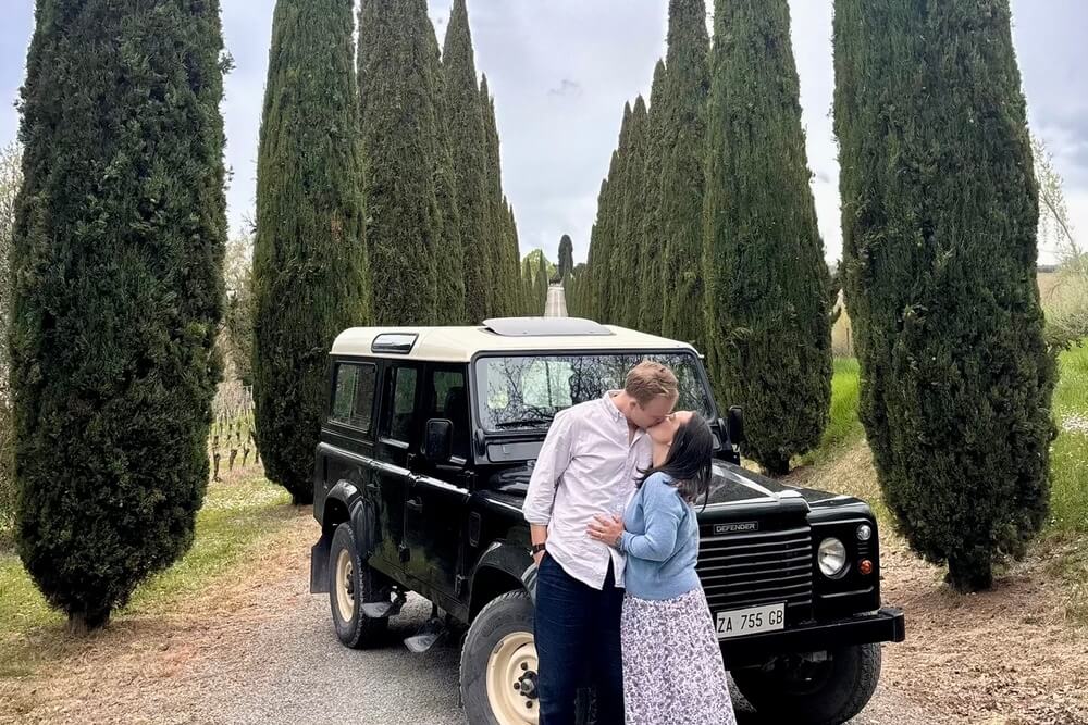 Marcus Conrad and his wife posing next to a car in Italy.