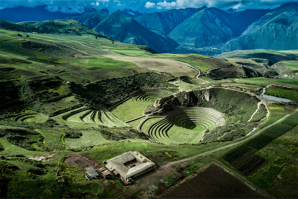 Moray sacred valley, the Incan site of Peru surrounded by mountains and green fields.