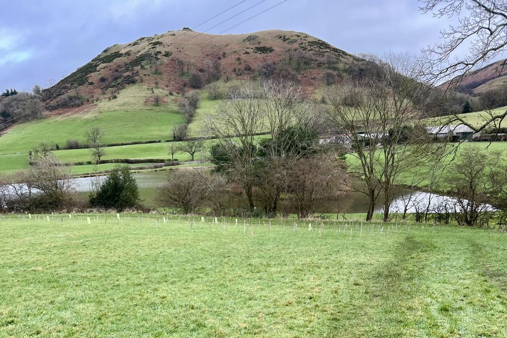 The view towards Caer Caradoc, a small lake, and green fields, Shropshire, England.