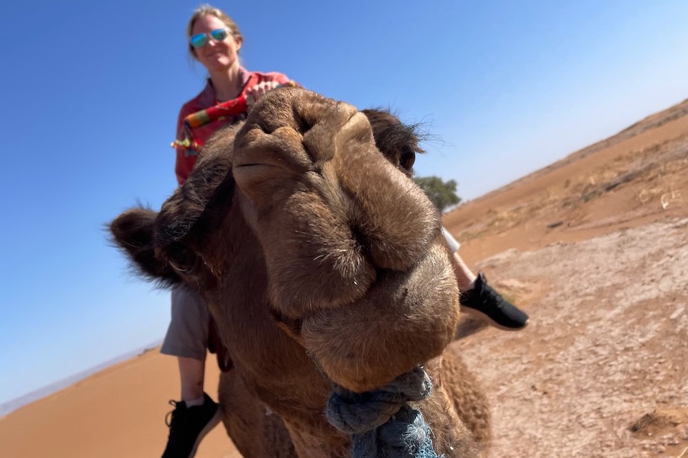 Brook Wilkinson riding a camel in the Sahara Desert, in Morocco.