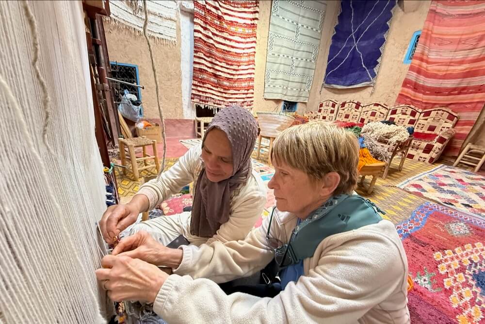 Susan Crandell learning weaving from a local at a rug store in Morocco.