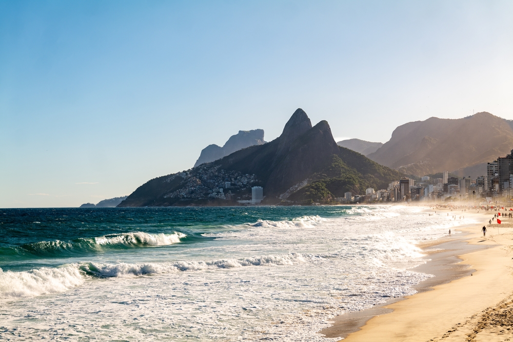 Morning waves with people walking on Ipanema beach in Rio de Janeiro, Brazil.