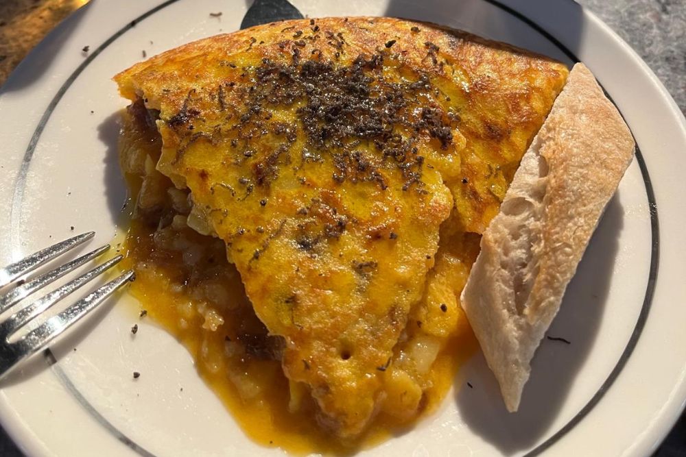 Tortilla de patata with a piece of bread, a Spanish dish.